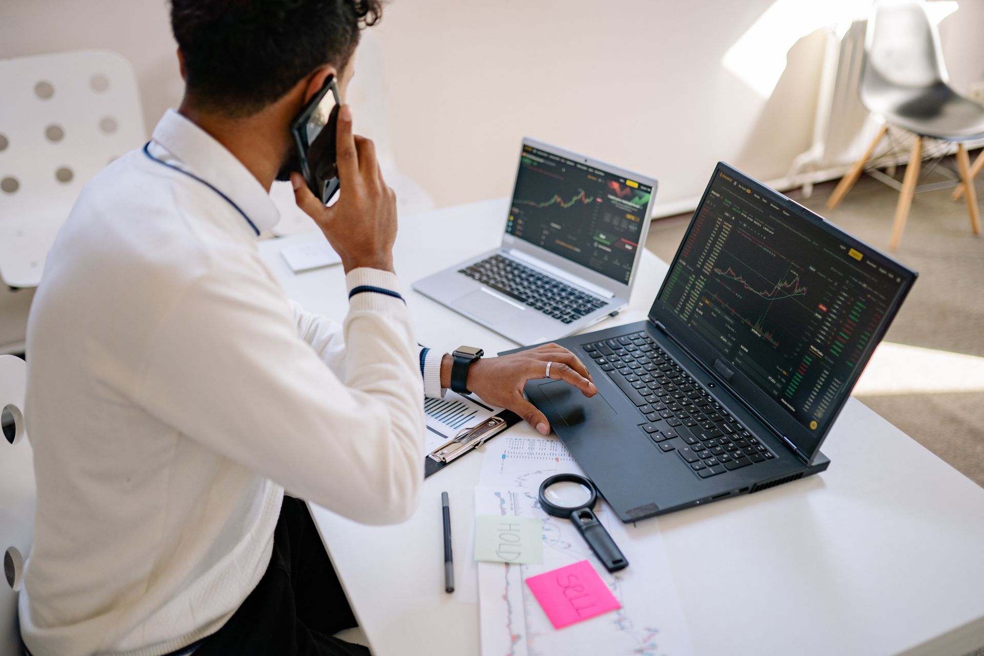 Business professional working on laptop and talking on phone in modern office